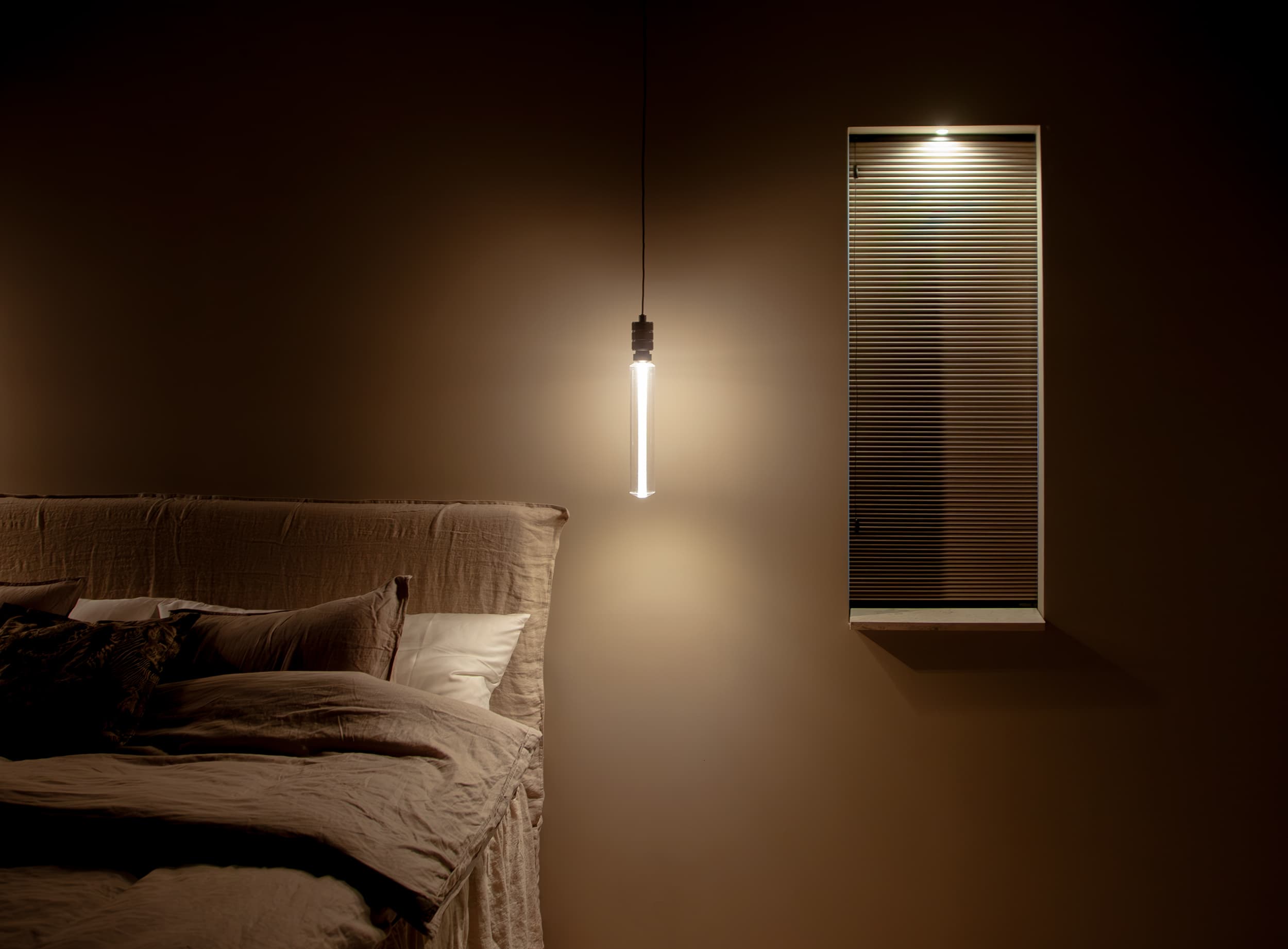 Sovrum naturfärg intredning smalt fönster med beige plisse gardin lampa lyser upp nisch